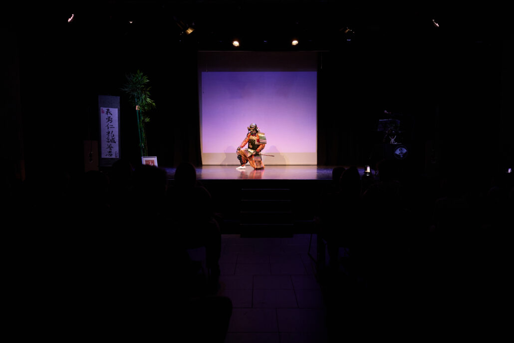 Escenario al fondo, con samurái vestido con armadura